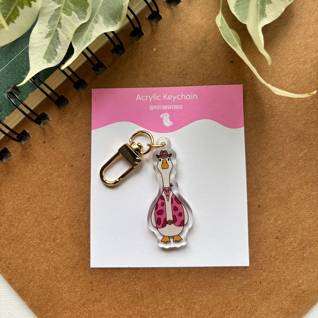 Acrylic keychain on a card with leaves and notebook in the background