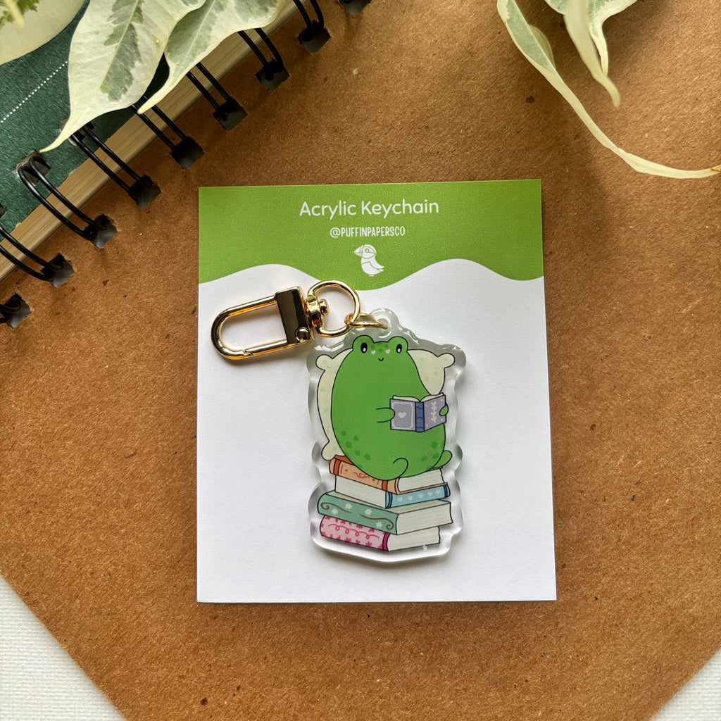 Acrylic keychain on a card with a plant and notebook in the background